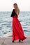 beauty woman in fluttering red dress at the coast. Fashion woman