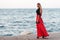 beauty woman in fluttering red dress at the coast. Fashion woman