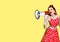 Beauty woman holding megaphone, shout advertising something. Girl in pin up style. Yellow color background with mock up copy space
