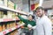 The beauty of a young couple buys canned vegetables in a supermarket. Portrait of a smiling man in a supermarket