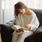 Beauty young woman is reading a book at home. Thoughtful girl reading important book