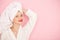 Beauty Young woman with red lips standing in the bath robe and towel on the head on the pink background. Studio shot