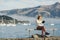 Beautyful asian woman resting is looks at the sea bay with houses and boats on a sunny day at Childrens bay, Akaroa, Canterbury,