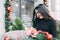 Beautyful young girl unpacks her box with a christmas gift. Woman with a gift in her hands stands on the background of Christmas d