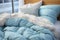 A bed with blue blanket and pillows on top of it