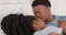 Bed, love and happy black couple romance kiss relax together on honeymoon or holiday vacation. Married African American