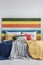 Bed with pillows, blankets and bedhead with rainbow colored wood