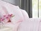 Bed with pink bed linen against a window with grey curtains