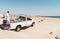 Bedouin man over the white 4x4 off-road car on the Al Khaluf beach in Oman