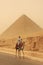 Bedouin riding camel near Great Pyramid of Khufu in a sand storm