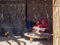 Bedouin village in desert, Egypt - February 2020: two arabian girls preparing food near fireplace, medium view. Shack