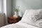 Bedroom closeup view. Striped white and beige linen pillows and blanket. Wooden bed and night stand. Blooming muscari