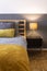 Bedroom detail with black bedside table and lit lamp. Wooden bed and floor