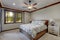 Bedroom interior with beige walls and wood trim and ceiling fan