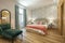 bedroom with king size bed with green velvet upholstered chaise longue seat, wooden floorboards in a vacation rental