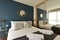 Bedroom with silver cushions, blue colored wall, fitted wardrobe with mirrored sliding doors and matching gold bedside tables with