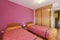 bedroom with two beds with pink walls, built-in wardrobe with sliding