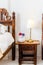 Bedside table with white lamp in the bedroom with vintage wooden bed