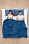 Bedtime. Young couple lying under blanket on bed top view browsing internet on smartphone concentrated