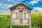 Bee box and insect hotel on a meadow next to a yellow flowering rape field with German writing - Hotel of the wild bee - , Germany