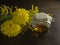 Bee honey in a glass jar with cover of burlap, a wooden spatula and yellow flowers on a dark background. Healthy food, farm