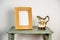 beech blank photo picture frame mock up with retro antique pouring jug on a green wooden table plain background