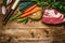 Beef brisket with vegetables ingredients for soup or broth cooking on rustic wooden background, top view