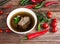 Beef broth with meat in white bowl with vegetables on wooden table