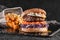 Beef burger with cabbage, carrot, fried eggs, sauce and fried stick balls, french fries on slate black background, close up