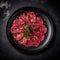 Beef Carpaccio On A Black Round Plate, French Dish. Generative AI