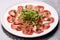 Beef carpaccio cold appetizer with parmesan, capers and arugula on white plate