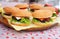 Beef and cheese burgers with green salad and sauce lying on a wooden plate at street food festival