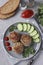 Beef cutlets served with cucumber and tomato sauce on a gray plate on gray concrete background, Vertical format