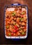 Beef goulash with vegetables and marjoram in blue baking dish on rustic wooden background