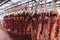 Beef half carcasses hanging on hooks in the slaughterhouse. Meat processing plant, cutting meat.