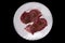 Beef heart slices in a white plate, on a black background