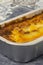 Beef lasagne or lasagna ready bfrozen meal cooked in a metal baking tray on a blue tea towel.