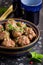 Beef meatballs in bowl with sauce, brown with sesame and parsley