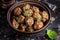 Beef meatballs in bowl with sauce, brown with sesame and parsley