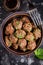 Beef meatballs in bowl with sauce, brown with sesame and parsley