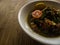 Beef rawon in a white bowl on a wooden patterned table