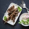 Beef skewers and rice noodles vegetables salad on a dark background, top view. Asian style