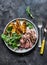 Beef steak and baked young potatoes - delicious lunch on a dark background, top view