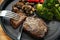 beef steak is cut with knife and fork, with vegetables like broccoli, mushrooms and tomatoes, low carb diet dinner on a dark gray
