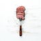 Beef steak on a fork. On a wooden background.