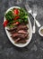 Beef steak and kale, tomato salad - delicious balanced diet lunch on a dark background, top view