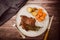 Beef steak served on a plate with rustic potatoes and carrots on a wooden table. Aerial view