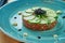 Beef steak tartare with black caviar and cucumber on a blue plate. Restaurant serving. CLose up view. appetizer