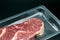 Beef steak, view of fresh beef in foil wrapper on dark background