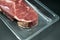 Beef steak, view of fresh beef in foil wrapper on dark background